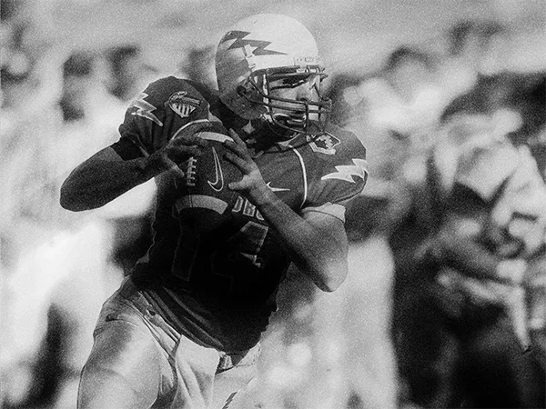 A quarterback dropping back to pass, in grainy black and white