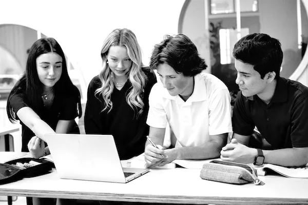 Four students working together around a laptop