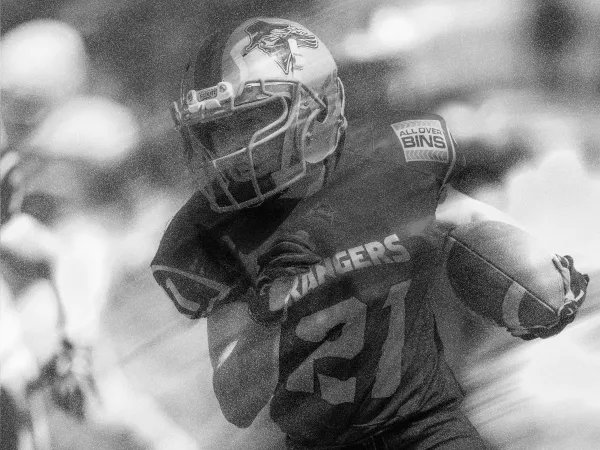 A running back carrying the ball, in grainy black and white